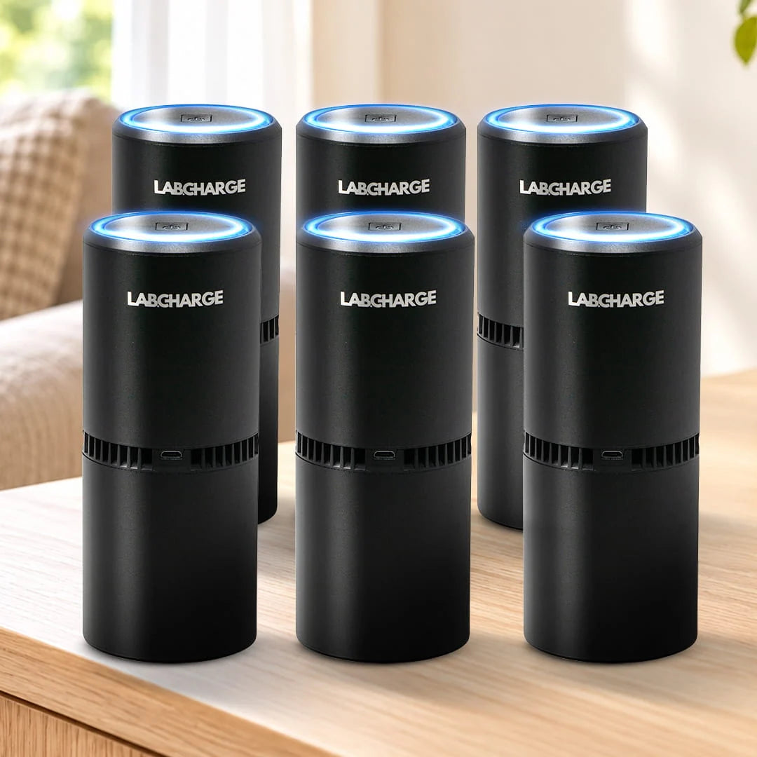 6 black Labcharge air purifiers on a light oak table in a neutral living room